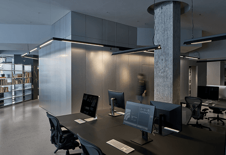 A shared office with desks, computers and pendant lighting